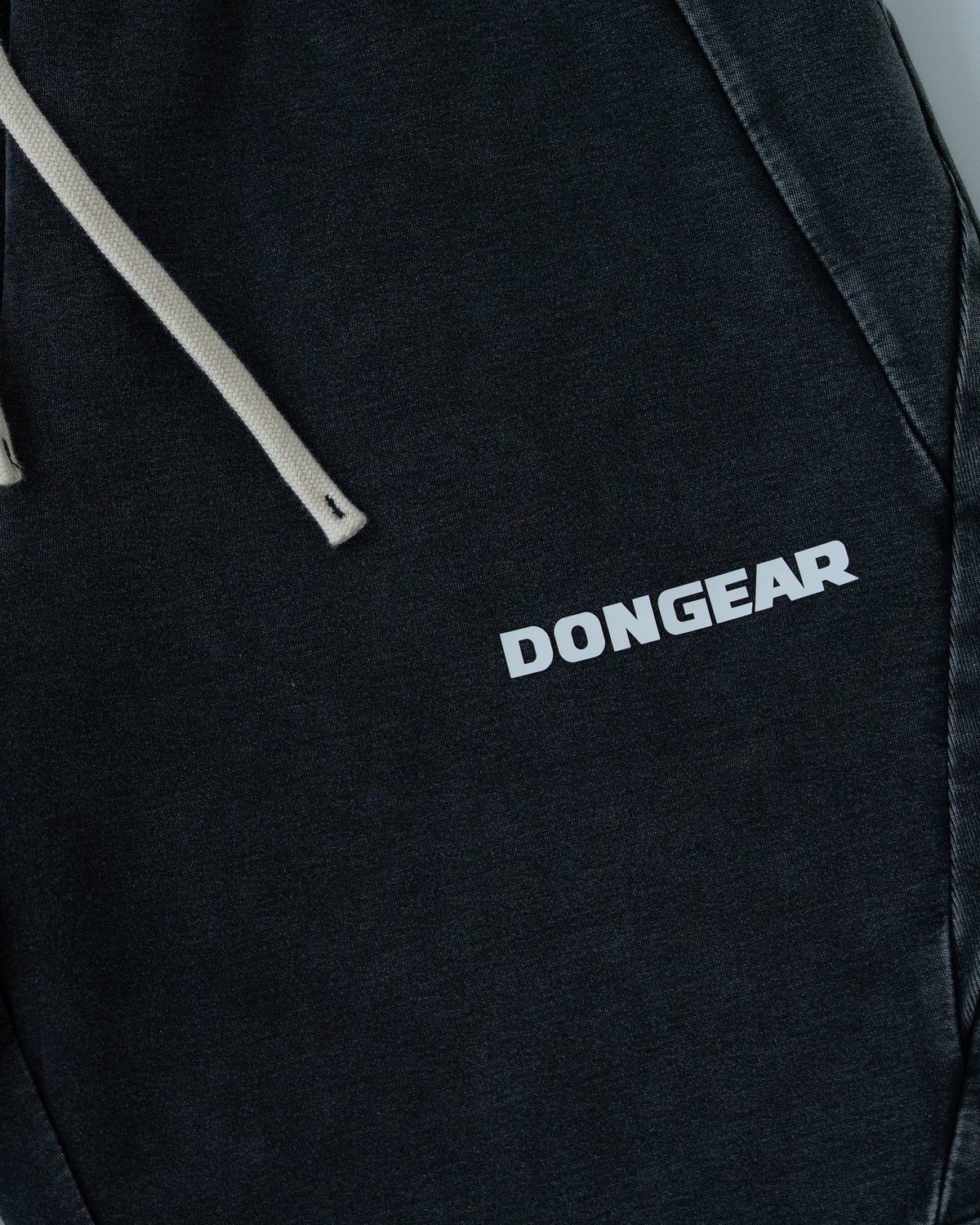 The Standard Shorts in Black, detail of the drawcord and wordmark