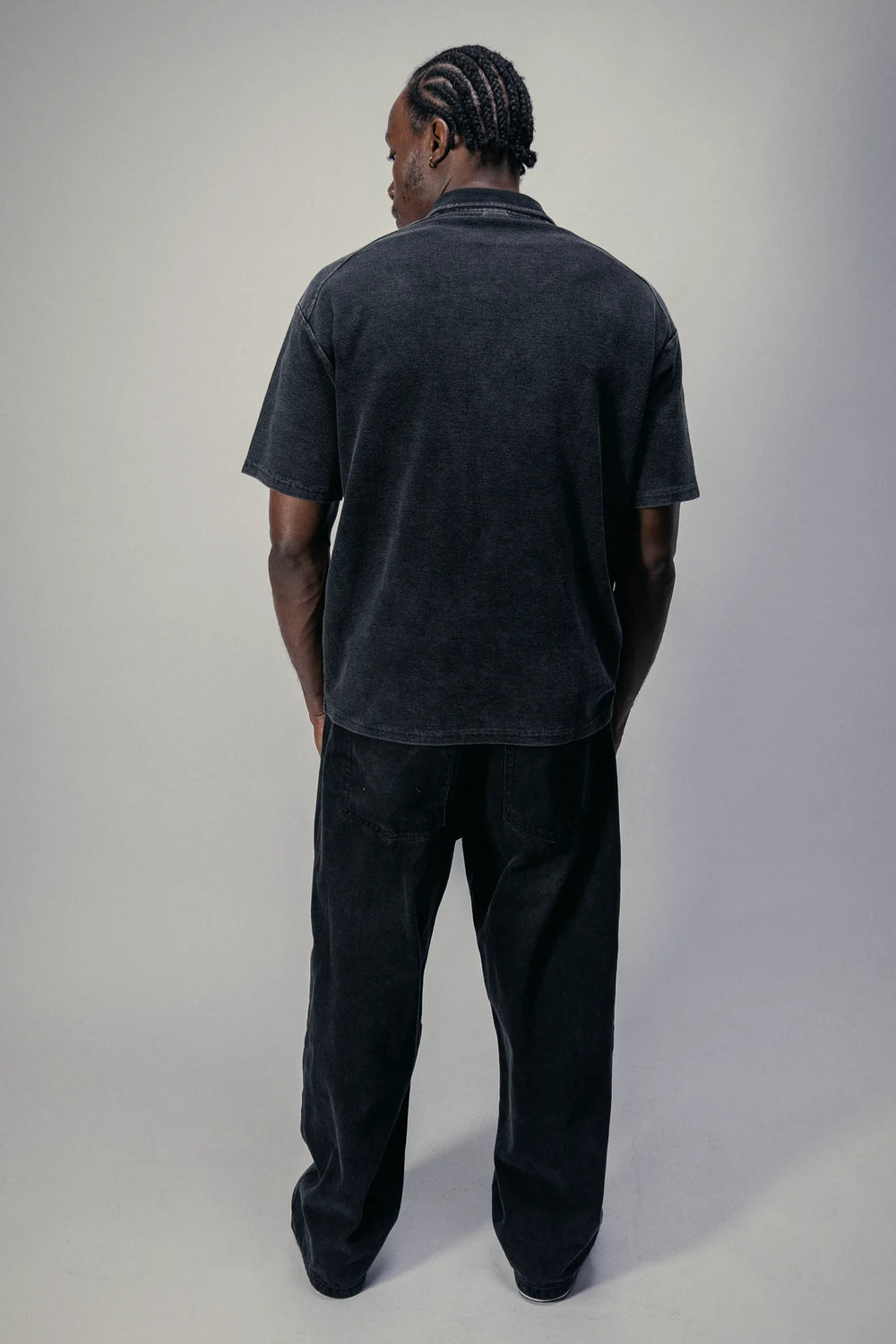 Short-sleeve zip polo in Black, worn with black trousers, back