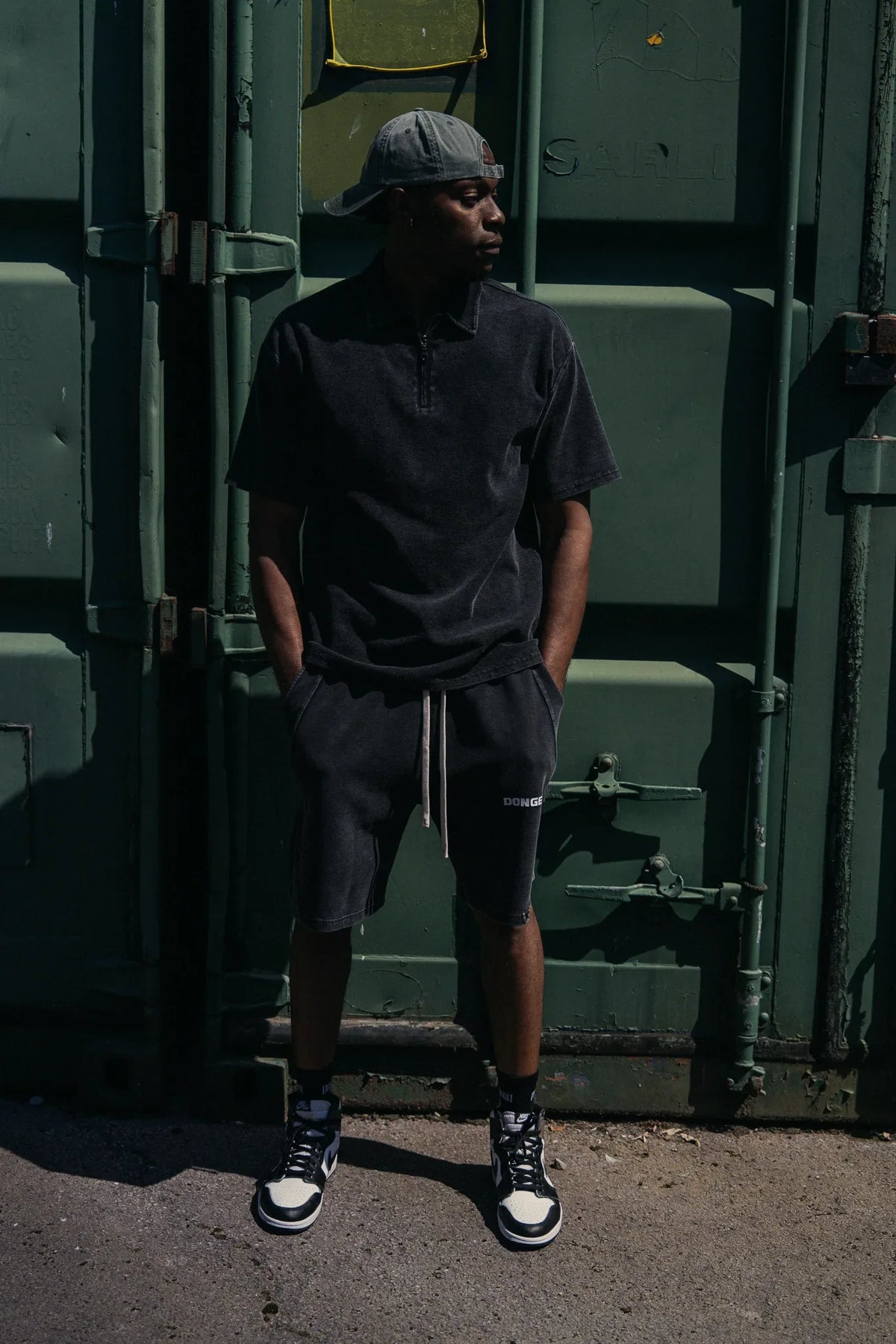 The Standard Zip Polo in Black, worn with The Standard Shorts in Black