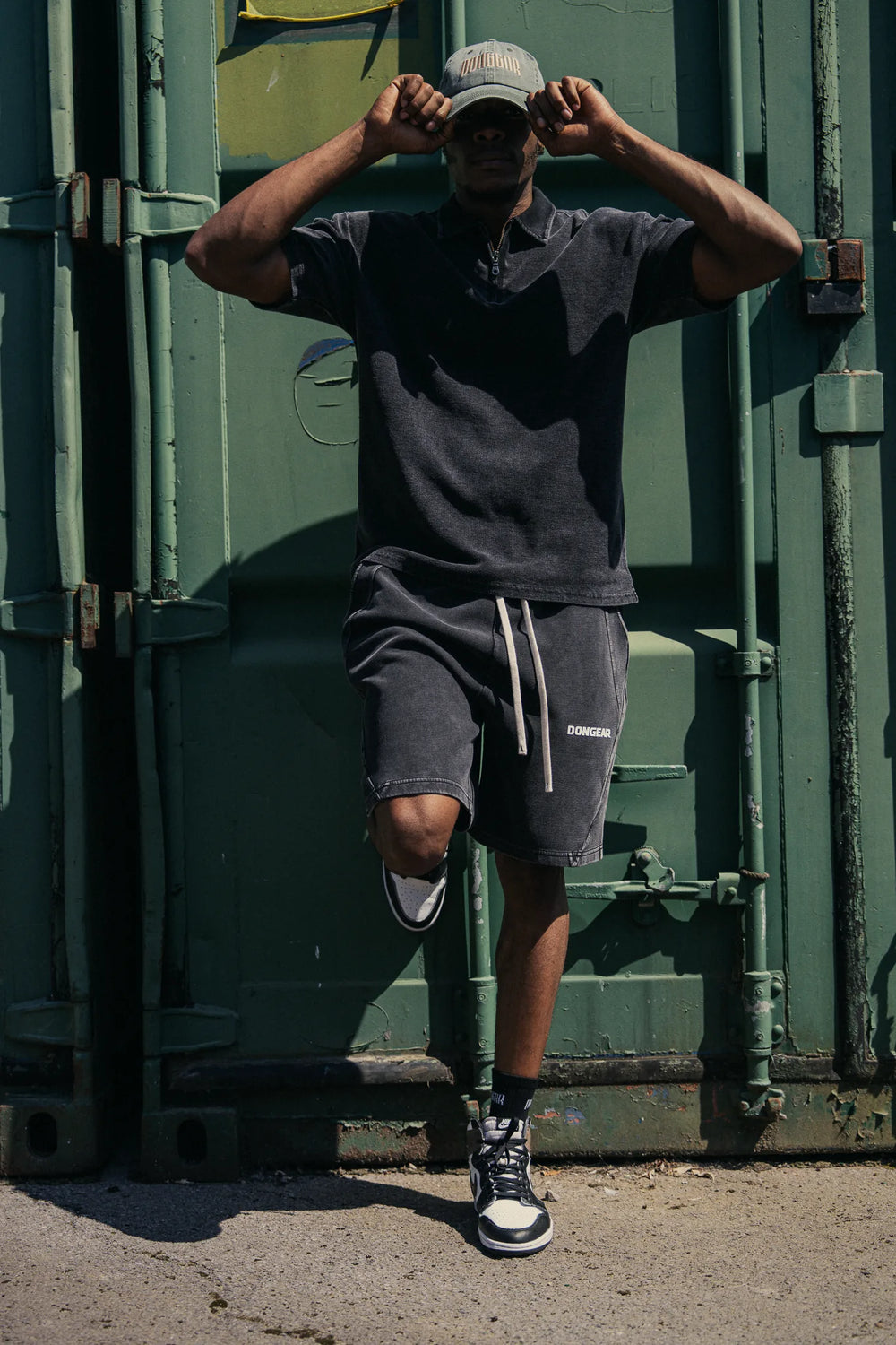 Short-sleeve zip polo in Black with matching shorts, hands on cap
