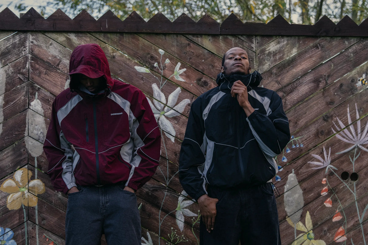 The Contour Tech Jacket in Oxblood and Black against a painted wall